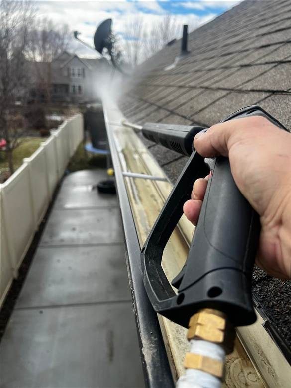 Pressure-washing debris out of a roof gutter — gutter cleaning service, Charlottesville, VA