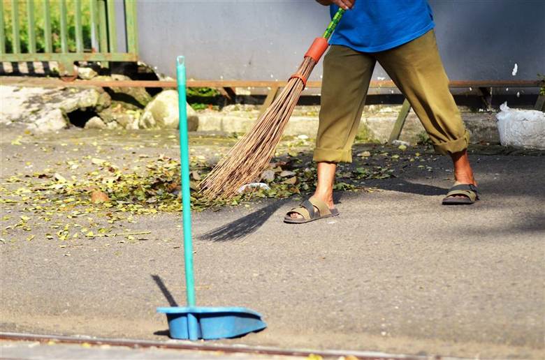 Sweeping fallen leaves off a driveway — leaf removal service